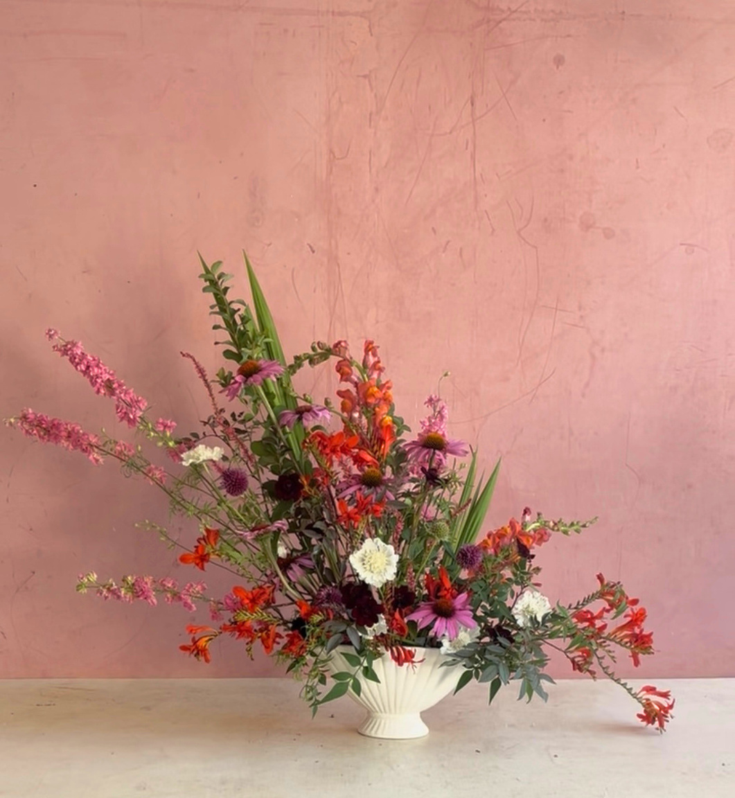 Red and pink arrangement against a rose wall