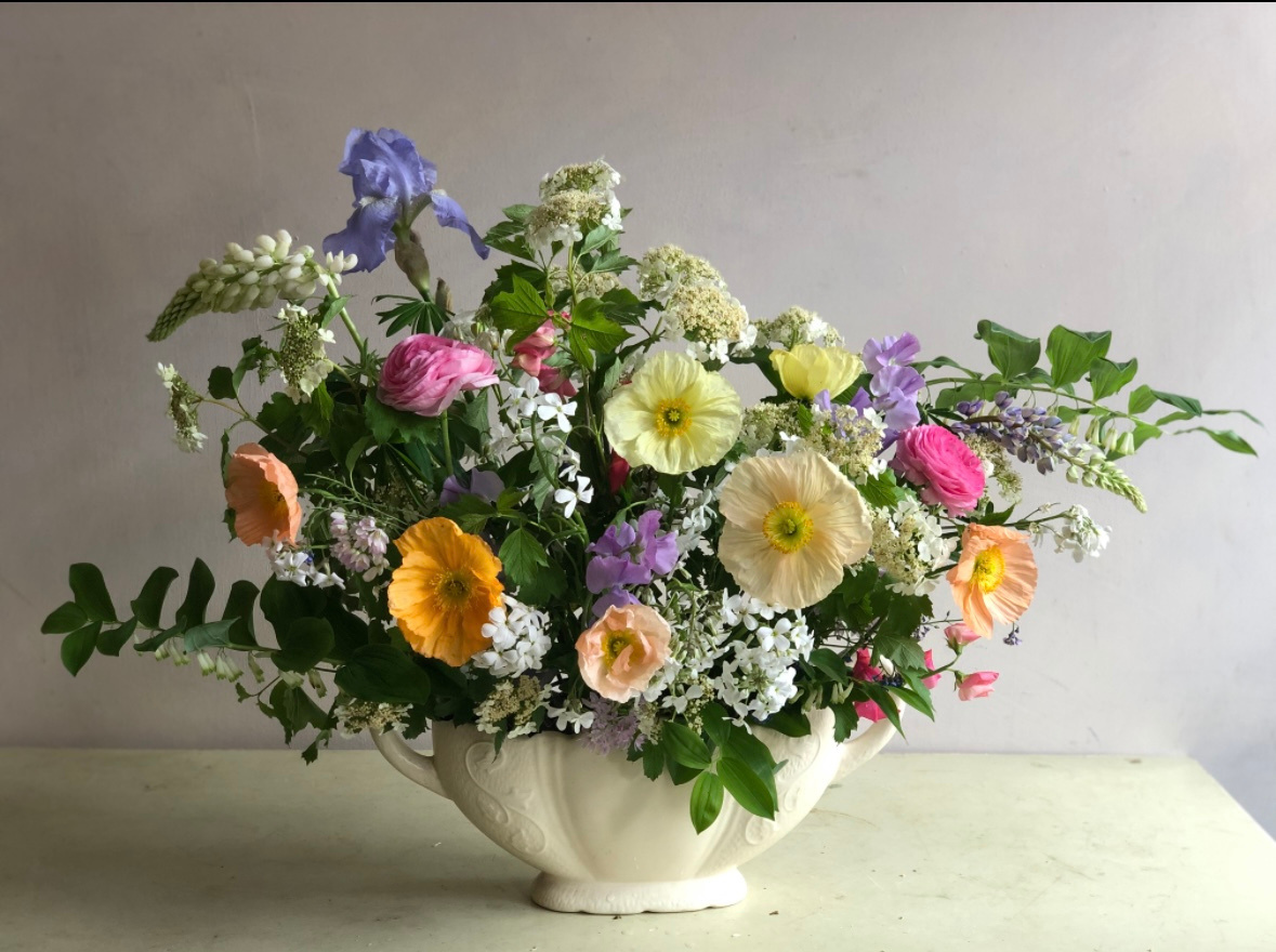A mixed arrangement in a ceramic bowl on a plinth