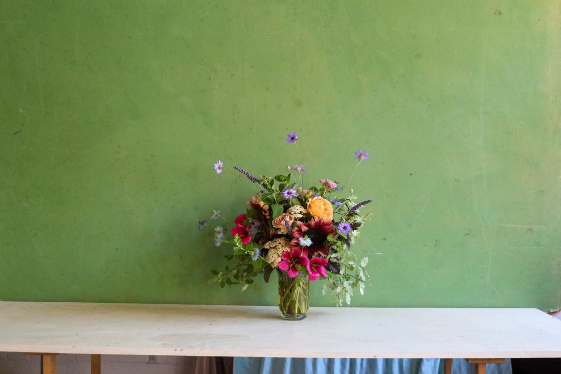 Florist’s choice bouquet in a glass vase against a green wall